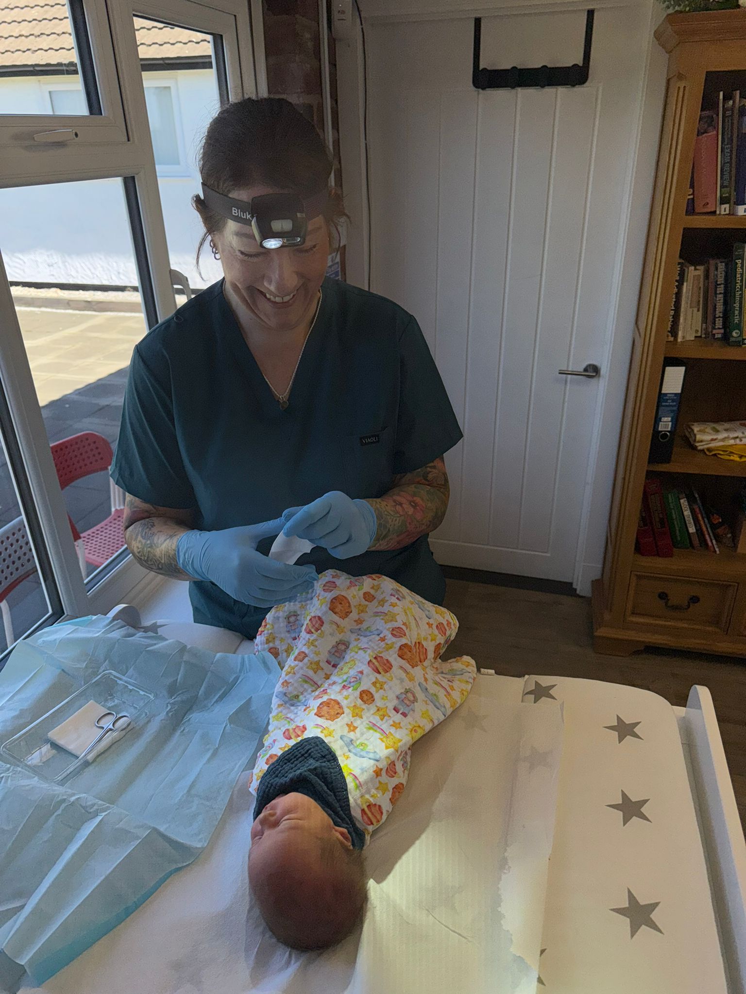 Sharon wearing a head torch ready to check a small baby for tongue-tie in an assessment